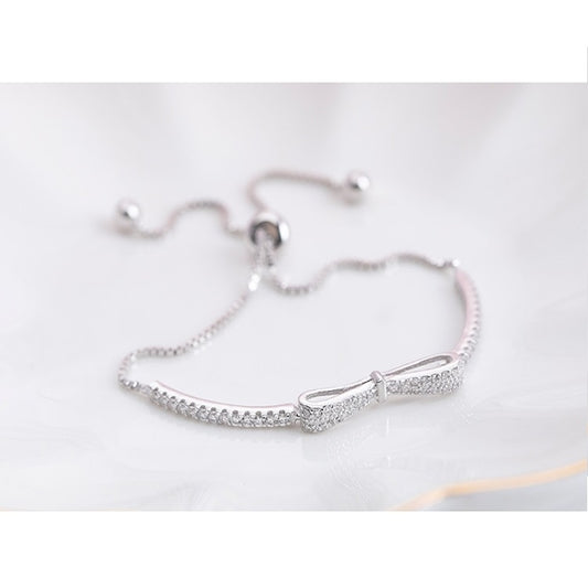 Silver bow stretch bracelet with heart-shaped sparkle charm and bead clasp