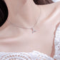 Silver whale-tail necklace on model’s neck with rhinestone pendant
