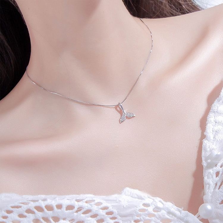 Silver whale-tail necklace on model’s neck with rhinestone pendant