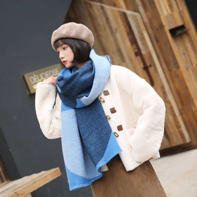 Blue geometric scarf worn with a light coat; fringed ends