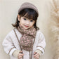 Child wearing knitted leopard-pattern scarf, mauve and brown, with knit hat