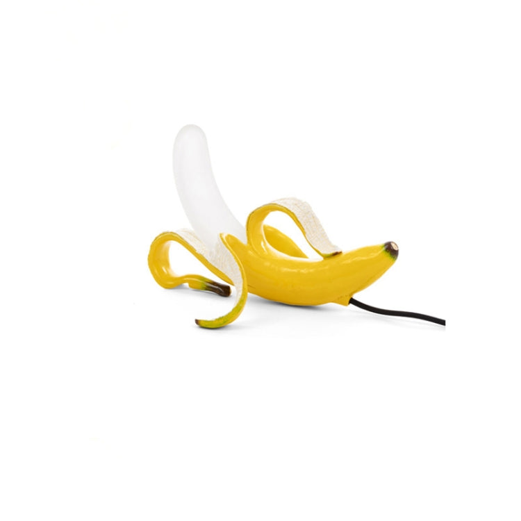 Banana-shaped table lamp with yellow banana, white peel, and black power cord