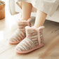 Beige knit indoor slippers with pink fuzzy trim, worn with light pants at home.