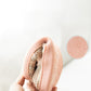 Beige knit slipper with pink lining and non-slip outsole tread pattern on the bottom.