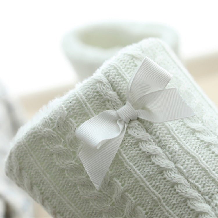 Close-up of white knit slipper boot with large bow and thick sole