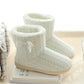 Pair of white cotton slipper boots with bow, cable knit texture, thick sole