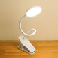 White clip-on LED desk lamp with curved neck and illuminated round diffuser