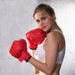 Red boxing gloves held up in a boxing stance, padded knuckles and wrist strap.