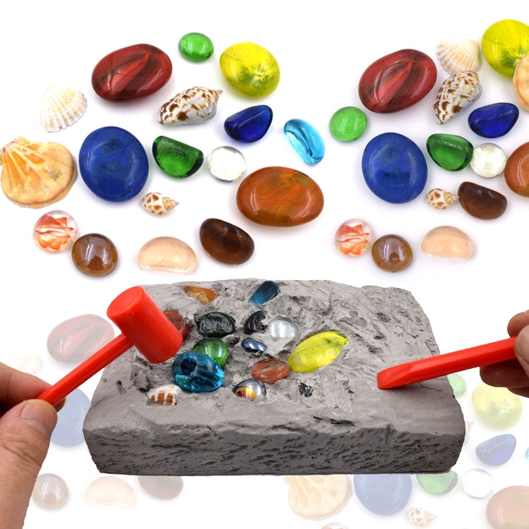 Gemstone dig excavation toy with gray rock, colorful gems, and two orange digging tools