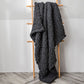Thick knitted wool blanket, dark gray, draped over a stand with textured loops