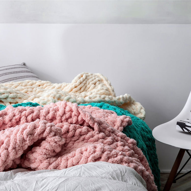 Chunky knit wool blanket in pink and teal with cream backing, layered on a bed