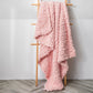 Thick knitted wool blanket, pink, folded and draped over a stand