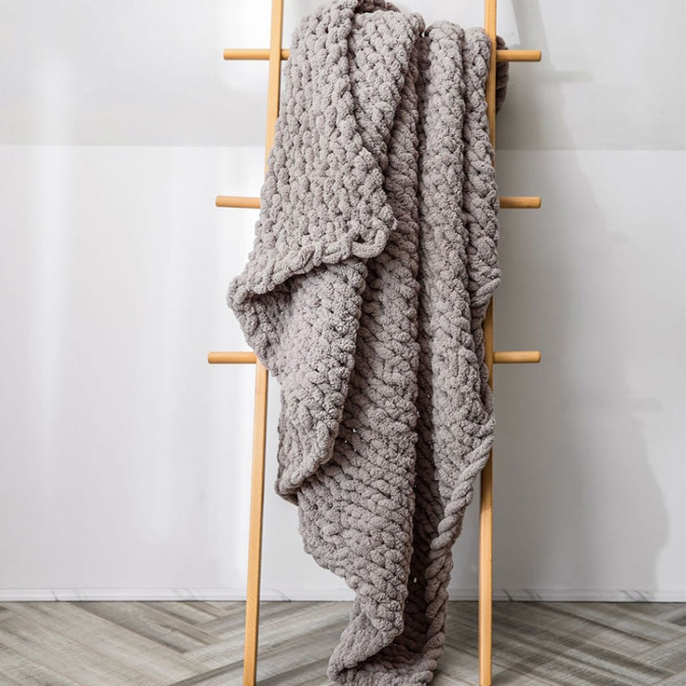 Thick knitted wool blanket, light gray, draped over a stand with chunky texture