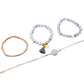 Bracelet set with white bead bangles, rose-gold chain bracelet, and round marble-style charm