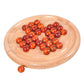 Round wooden chessboard with orange-red wooden balls and one loose piece