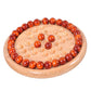Round wooden chessboard with orange-red pieces and beige grid dots