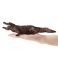Brown crocodile model toy being held in a hand, showing tail and open jaws