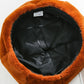 Plush beret hat with black inner lining, caramel/orange fuzzy outer.