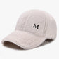White plush baseball cap with curved brim and embroidered M logo