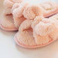 Close-up of light pink plush slippers with knotted bow and heart detail