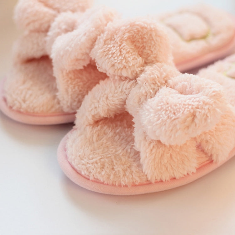 Close-up of light pink plush slippers with knotted bow and heart detail