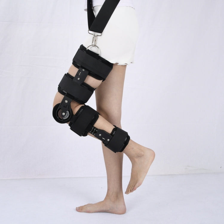 Black knee fixation brace worn on leg with adjustable straps and hinge supports