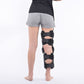 Adjustable black knee brace worn over shorts with padded side straps and hinge