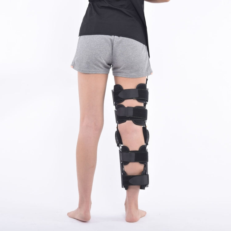 Adjustable black knee brace worn over shorts with padded side straps and hinge