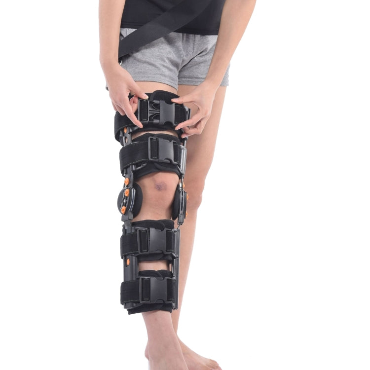 Adjustable black knee brace close-up with orange accents, pads, and side straps