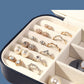 Open jewelry storage box with ring compartments and flannel dividers, navy outer frame