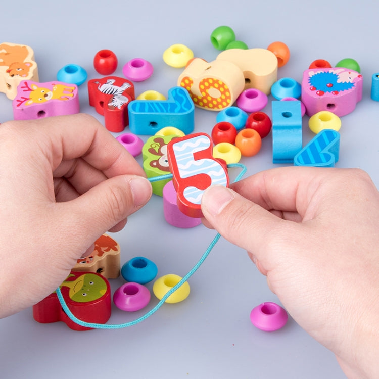Hands threading a blue string through a wooden number block with animal bead pieces