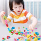 Child playing with wooden bead threading toy, placing colorful blocks on cords