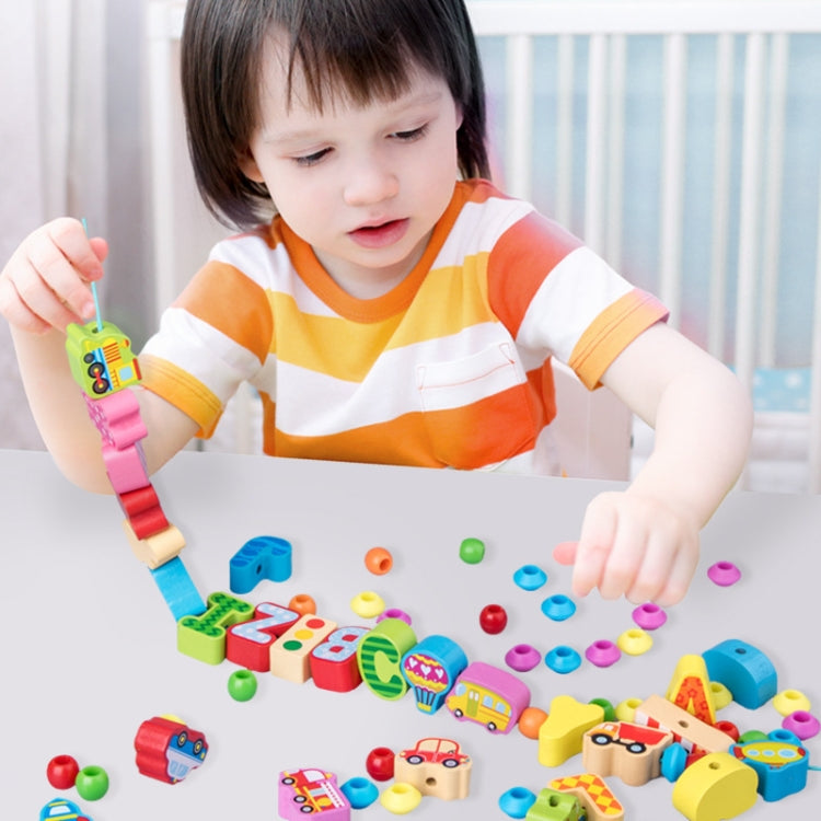 Child playing with wooden bead threading toy, placing colorful blocks on cords