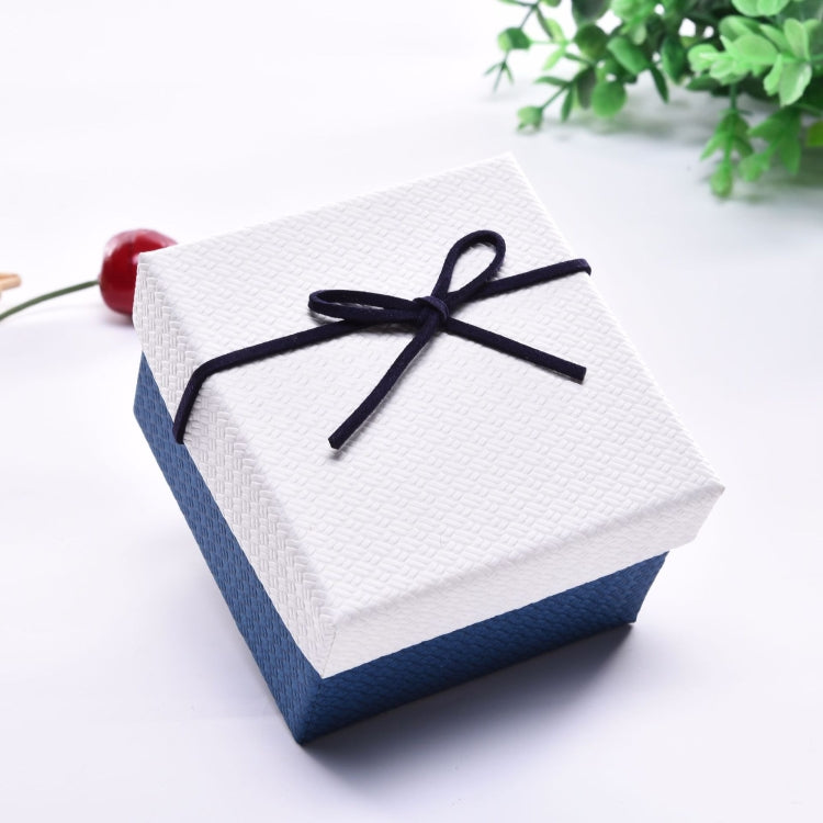 Small jewelry gift box with white lid, blue sides, tied with dark navy ribbon bow.