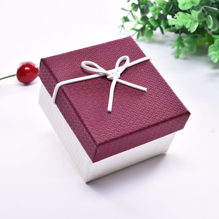 Small jewelry gift box with burgundy lid and white ribbon bow on top.