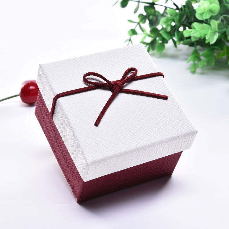 Small jewelry gift box with white lid, burgundy sides, and dark red ribbon bow.