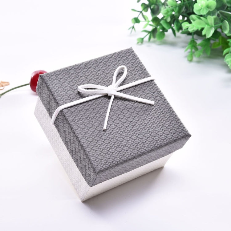 Small jewelry gift box with gray lid, light base, and white ribbon bow on top.