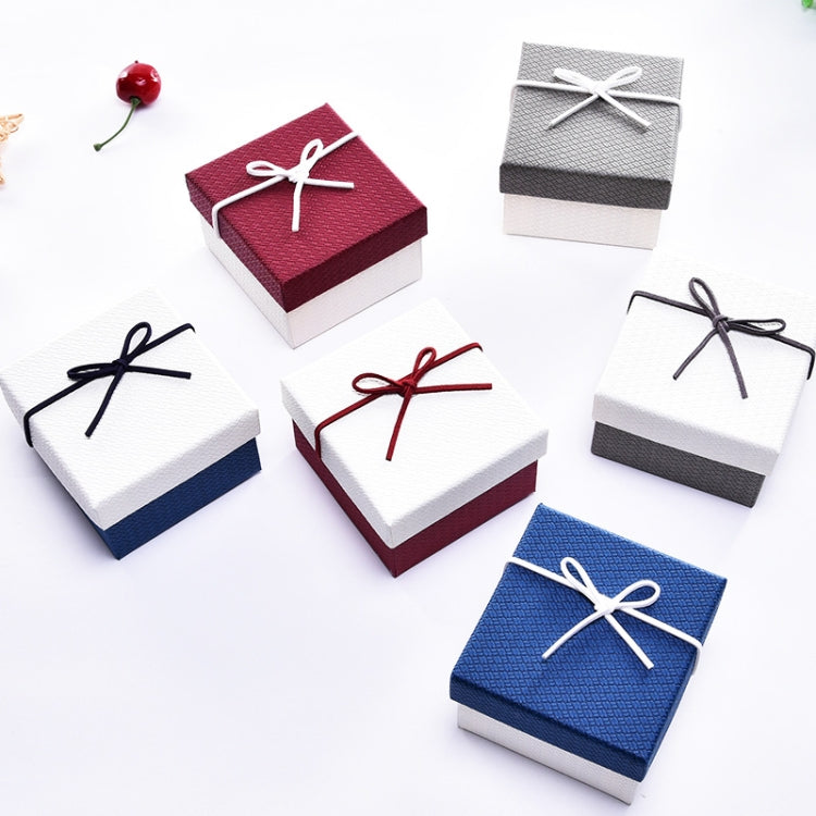 Assorted small jewelry gift boxes with ribbon bows in blue, white, red, and gray.