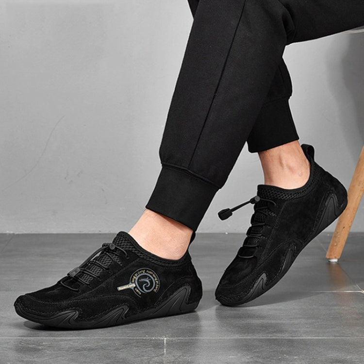 Black lace-up sneakers worn with black pants and low-profile rubber sole.