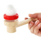 Wooden ball blower with white foam ball on red circular base; hand holding the handle