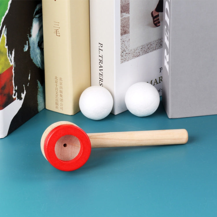 Wooden ball blower piece with red disc and long handle; two white foam balls in box