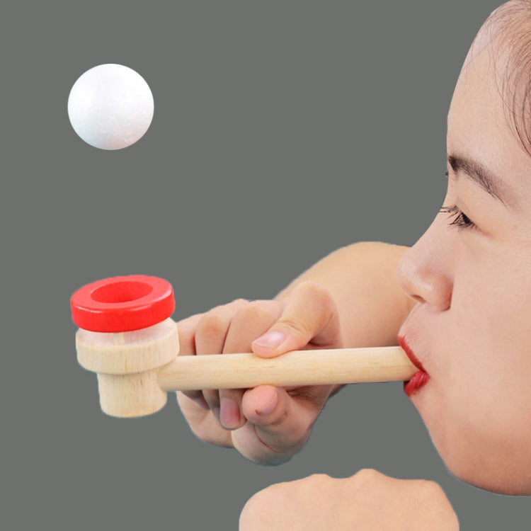 Wooden ball blower toy held in hand; red-ring base with white foam ball