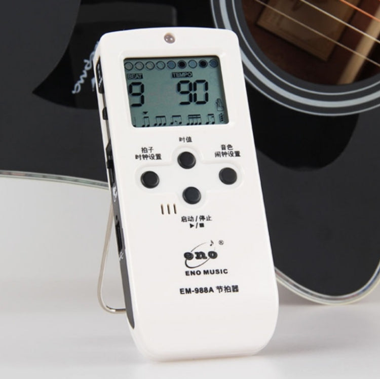 White electronic metronome close-up with LCD screen and round control knobs
