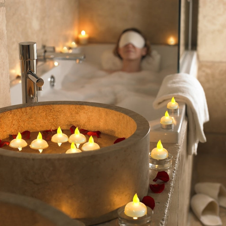 Warm white LED floating candles placed along a bathtub edge