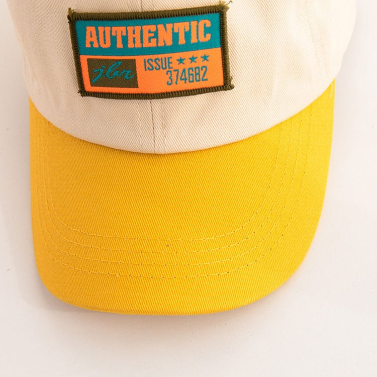 Close-up kids baseball cap: beige crown with embroidered “AUTHENTIC” patch on yellow brim