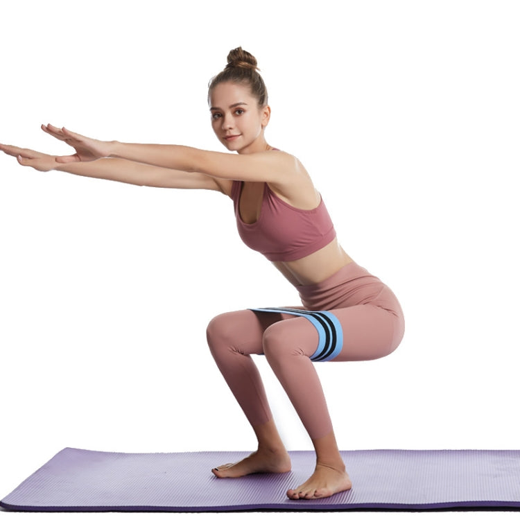 Blue resistance loop band with black stripes on thighs during squat exercise