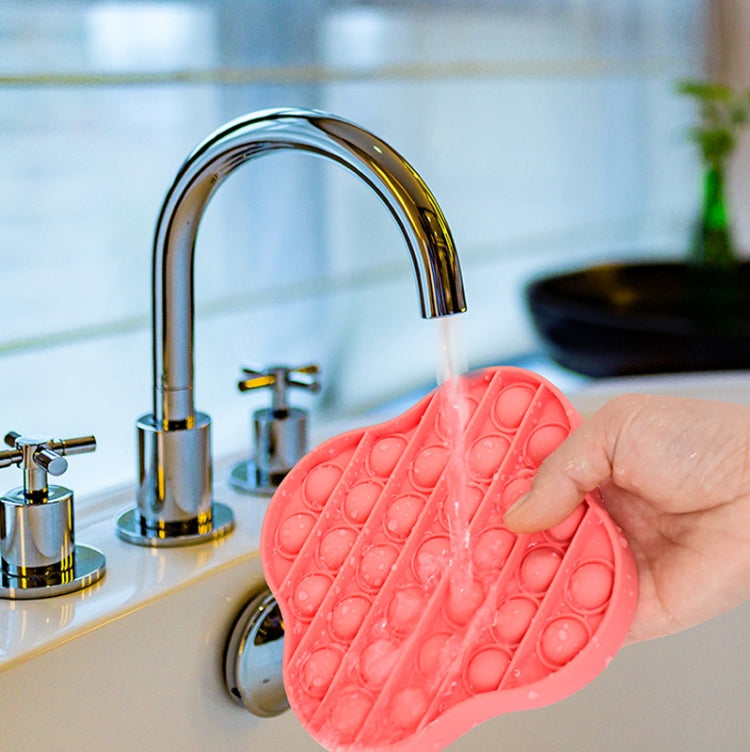 Coral-red silicone pop-it pressing board being pressed near a sink