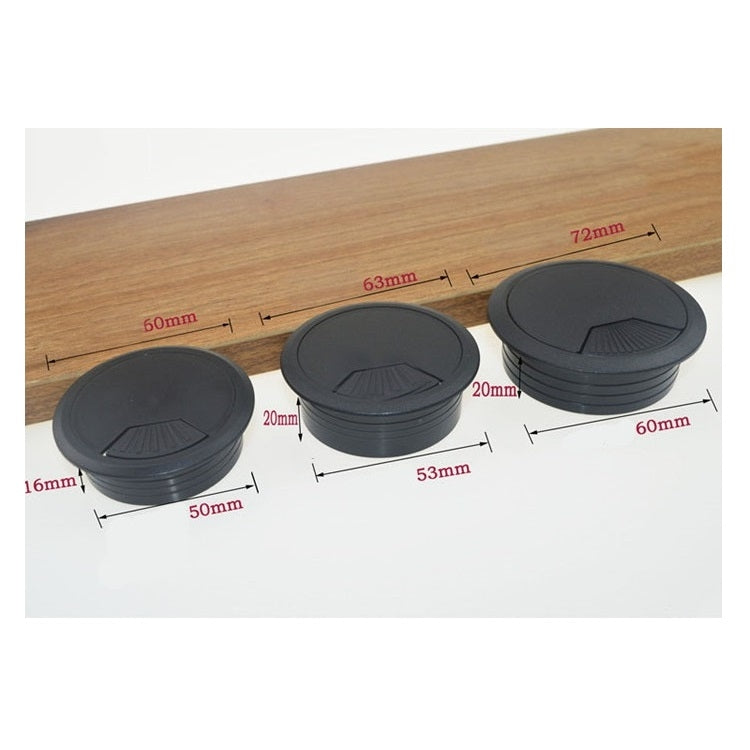 Set of round black desk cable hole covers on wooden tabletop, fluted surface for grip