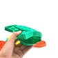 Green silicone car-shaped pop-it board with raised bubble buttons, held by hand