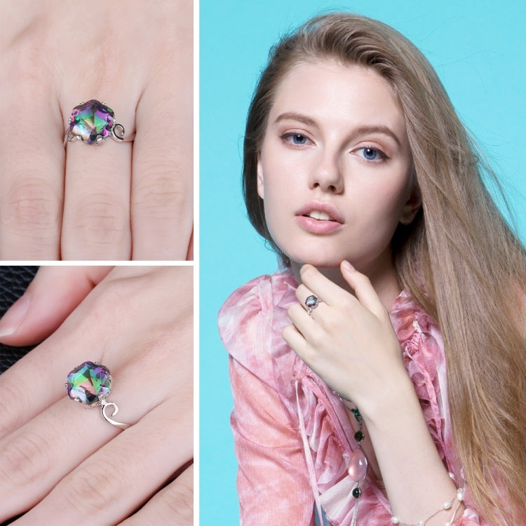 Multicolor faceted gemstone ring on hand, featuring a silver-tone band with decorative swirl